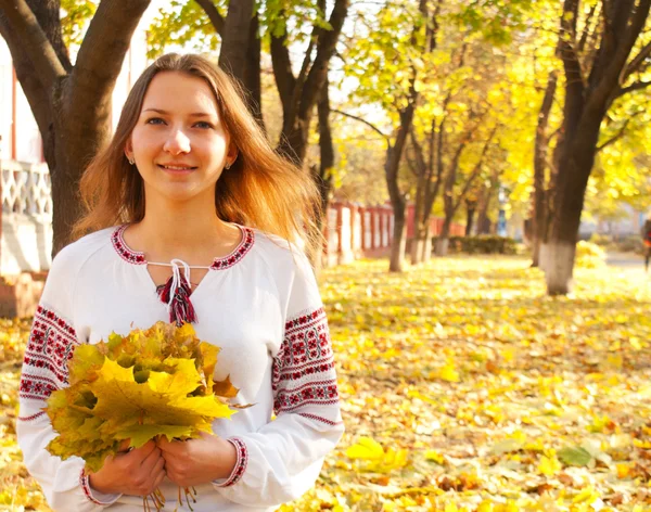 Young lady sitting in a park at fall time — Stock Photo, Image