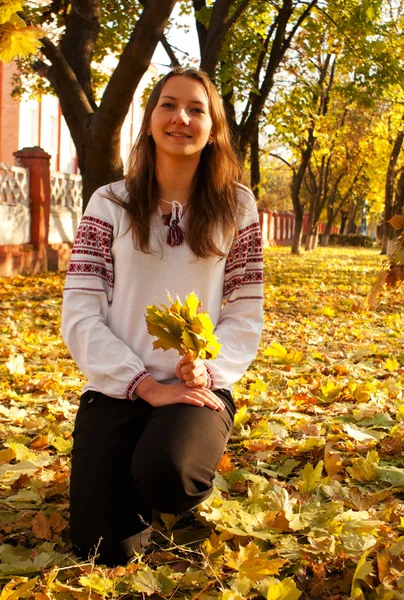 Young lady sitting in a park at fall time — Stock Photo, Image