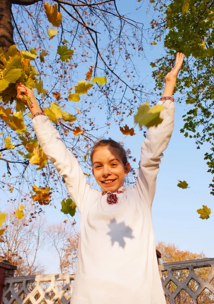 Девушка играет с листьями осенью — стоковое фото