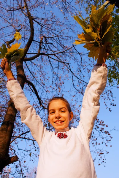 Menina brincando com folhas no outono — Fotografia de Stock