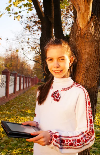 Tiener meisje met e-boek lezer in een park — Stockfoto