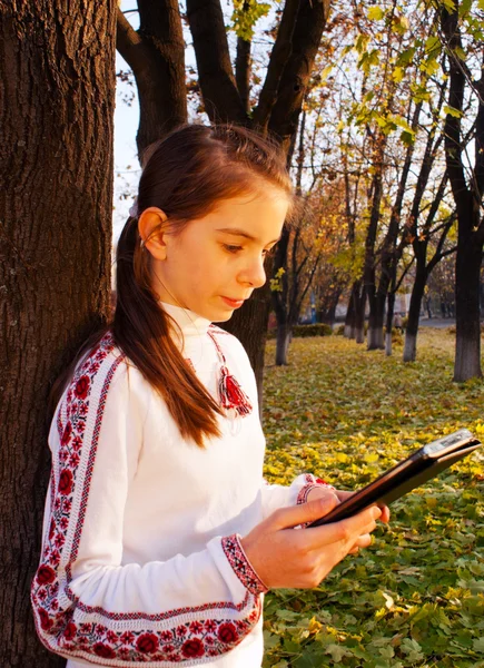 Menina adolescente com leitor de e-book em um parque — Fotografia de Stock