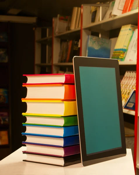 Montón de libros coloridos y lector electrónico de libros en la librería —  Fotos de Stock