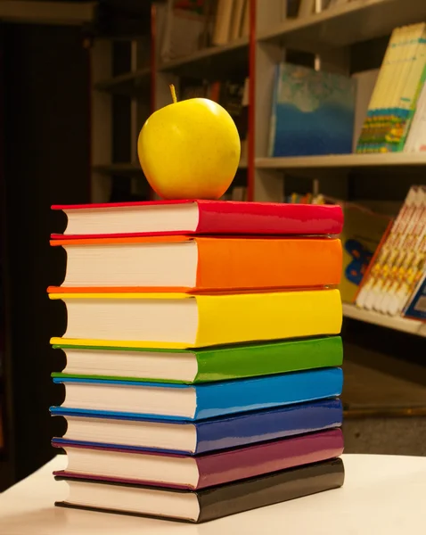 Купа різнокольорових книг з яблуком на ньому — стокове фото