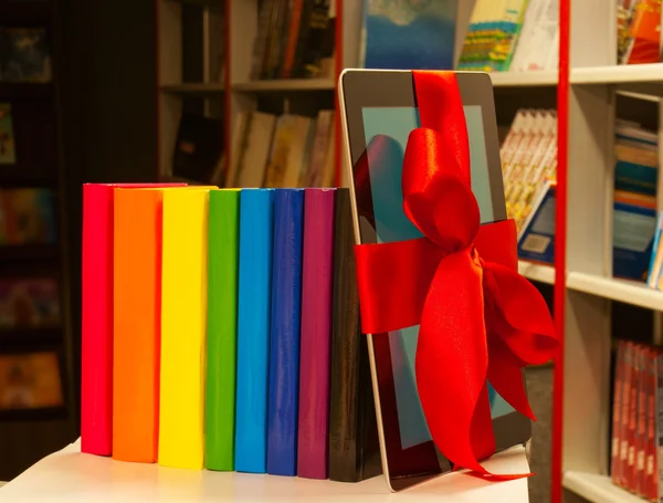 Elektronische boek lezer vastgebonden met een rood lint en rij van boeken — Stockfoto