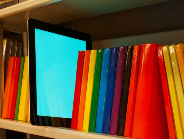 Fila de livros coloridos e leitor de livros eletrônicos na prateleira — Fotografia de Stock