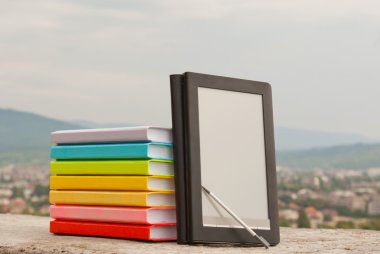 Stack of colorful books with electronic book reader clipart