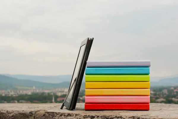 Stapel kleurrijke boeken met elektronische boek lezer — Stockfoto
