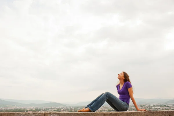 Молодая женщина, сидящая на улице на фоне голубого неба — стоковое фото