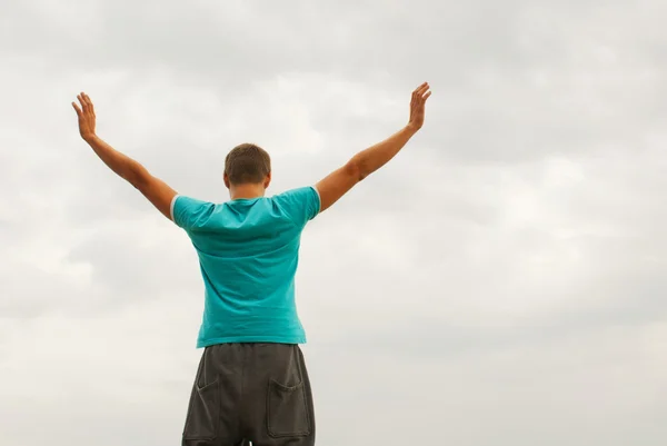 Молодий чоловік залишається з піднятими руками на блакитне небо — стокове фото