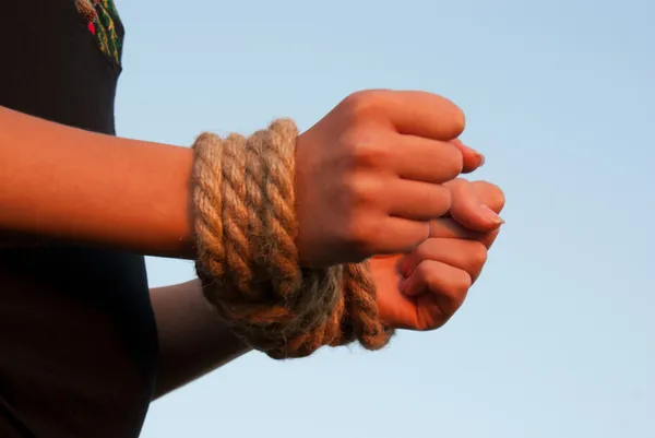 Mãos atadas com corda contra o céu azul — Fotografia de Stock