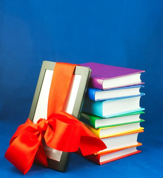 Leitor de livros eletrônicos amarrado com fita vermelha com pilha de livros — Fotografia de Stock