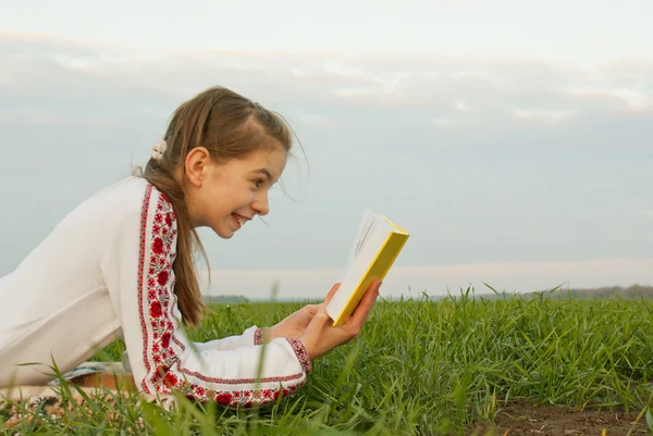 Menina adolescente lendo um livro em um campo — Fotografia de Stock