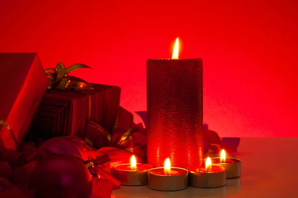 圣诞礼物和蜡烛在红色背景 — 图库照片