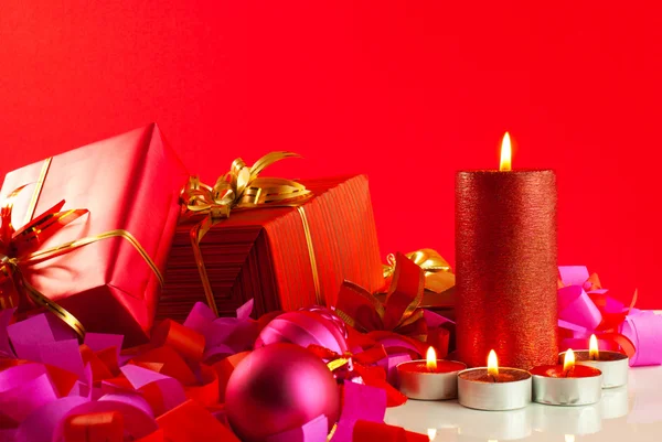 Presentes de Natal e velas sobre fundo vermelho — Fotografia de Stock