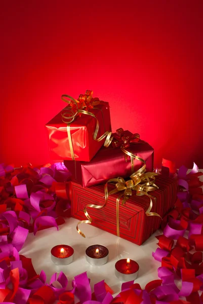 Christmas gifts and candles over red background — Stock Photo, Image