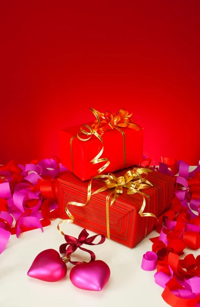 Valentýna dárky a srdce na červeném pozadí — Stock fotografie