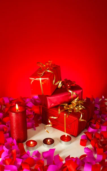 Рождественские подарки и свечи на красном фоне — стоковое фото