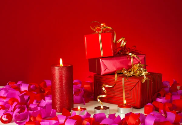 Regalos de Navidad y velas sobre fondo rojo — Foto de Stock