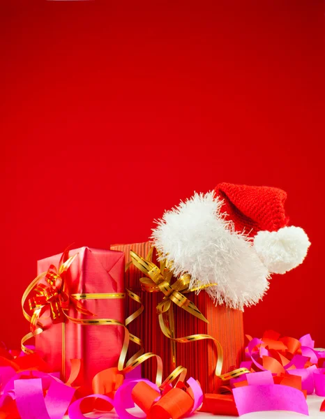 Regali di Natale con cappello di Babbo Natale sullo sfondo rosso — Foto Stock