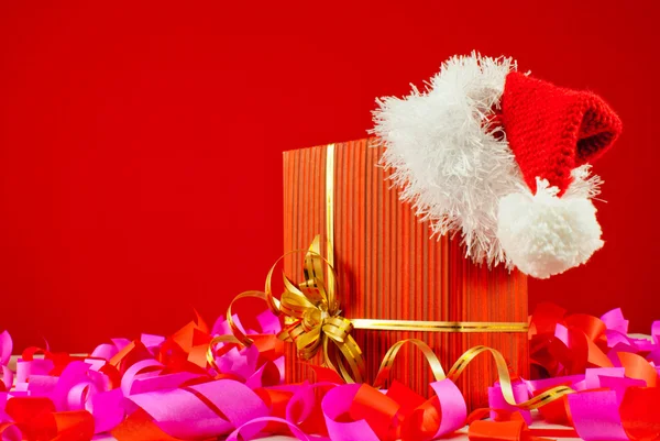 Regalo di Natale con cappello di Babbo Natale sullo sfondo rosso — Foto Stock