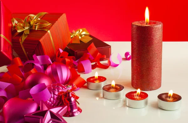 Regalos de Navidad y cuatro velas sobre fondo rojo —  Fotos de Stock