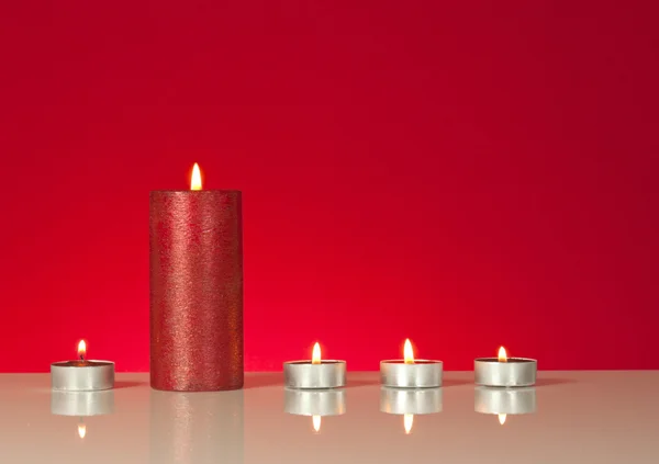 Cinq bougies allumées sur fond rouge — Photo