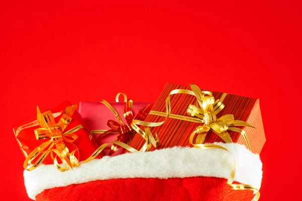 Presentes de Natal no saco contra fundo vermelho — Fotografia de Stock