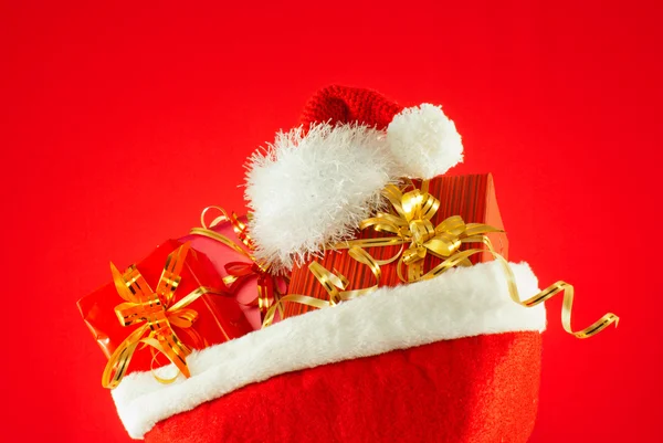 Presentes de Natal com chapéu de Papai Noel contra fundo vermelho — Fotografia de Stock