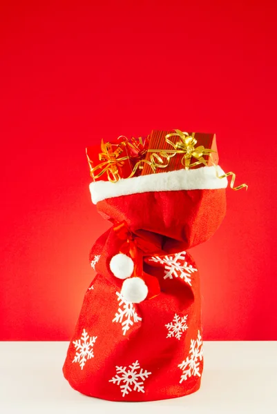 Weihnachtsgeschenke in der Tüte vor rotem Hintergrund — Stockfoto