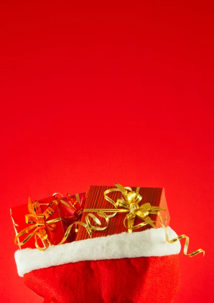 Рождественские подарки в сумке на красном фоне — стоковое фото