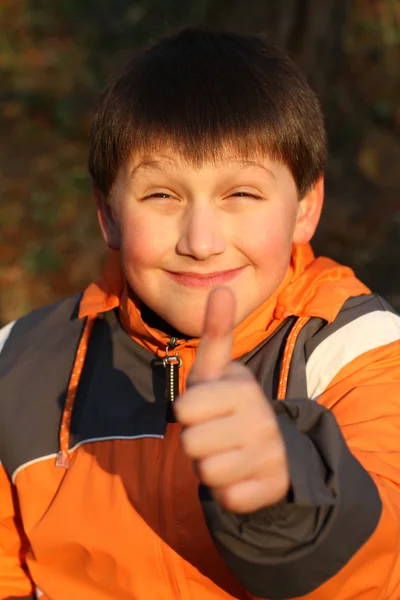 Portrait of young boy giving thumbs in the autumn park — Stock Photo, Image