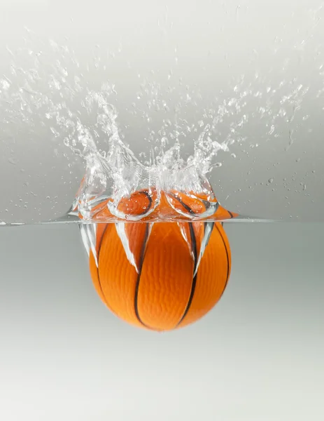 Falling basketball into water isolated on grey background — Stock Photo, Image