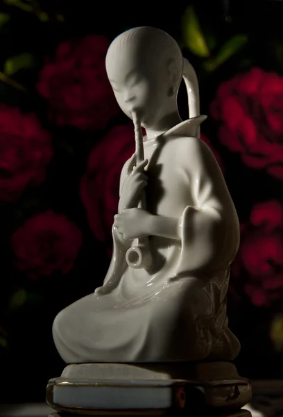 Китайская статуя на фоне красной розы — стоковое фото