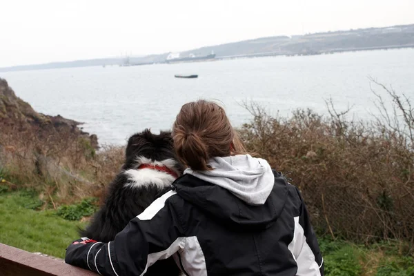 Feminino e cão olhando para o mar — Fotografia de Stock