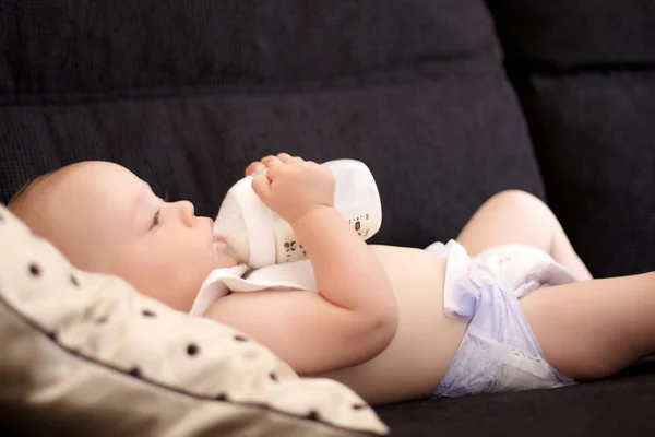 A six month old baby drinking out of his bottle — Stock Photo, Image
