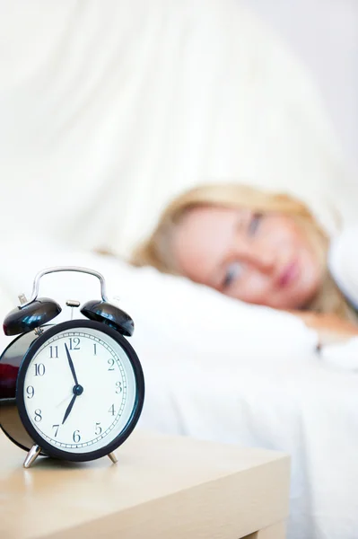 Žena spí v posteli a budík — Stock fotografie