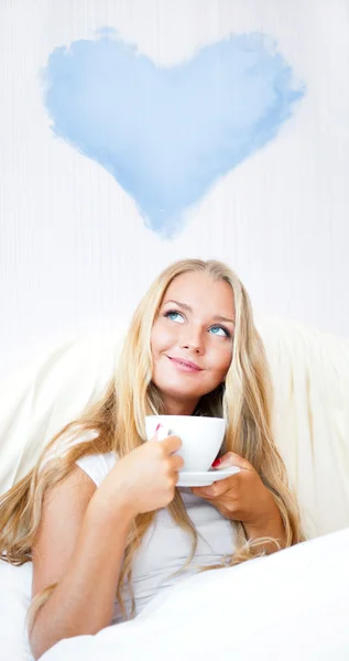 Νεαρή γυναίκα στο σπίτι πίνοντας τσάι ή καφέ από ένα κύπελλο και σκέψης — Φωτογραφία Αρχείου