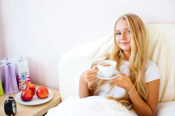 Νεαρή γυναίκα στο σπίτι πίνοντας τσάι ή καφέ από ένα φλιτζάνι — Φωτογραφία Αρχείου