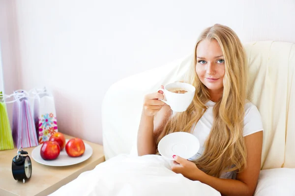 Mladá žena doma popíjeli čaj nebo kávu z hrnečku — Stock fotografie