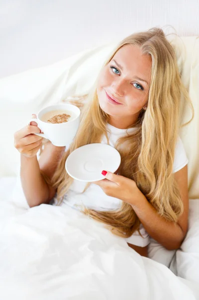 Νεαρή γυναίκα στο σπίτι πίνοντας τσάι ή καφέ από ένα φλιτζάνι — Φωτογραφία Αρχείου