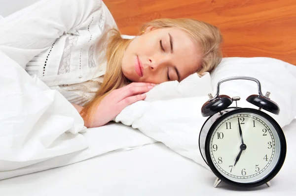 Young sleeping woman and alarm clock in bedroom at home — Stock Photo, Image