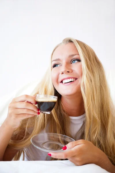 Donna sorridente che beve un caffè sdraiata su un divano a casa — Foto Stock