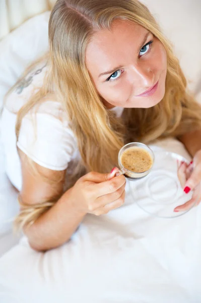 微笑着喝一杯咖啡，躺在家里的沙发上的女人 — 图库照片