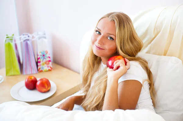 Młoda piękna kobieta z apple w łóżku w nocy — Zdjęcie stockowe