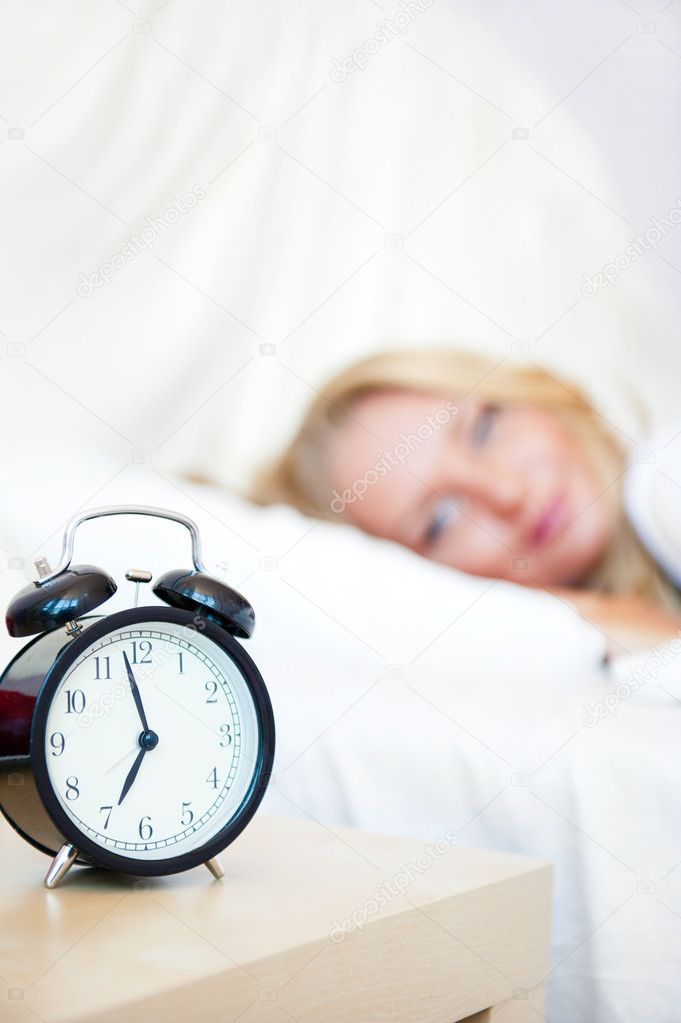 Woman sleeping in bed and alarm-clock