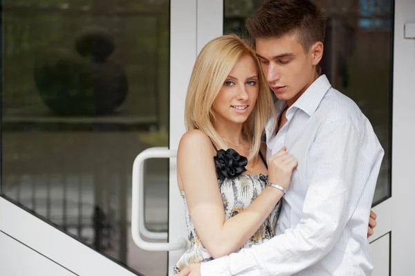 Acogedora pareja joven abrazándose en casa cerca de una puerta y mirando hacia fuera —  Fotos de Stock