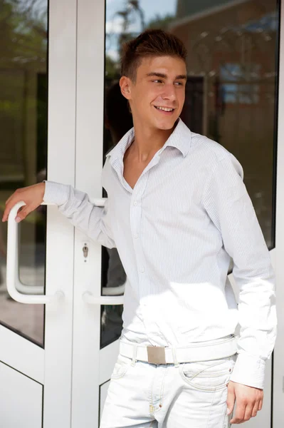 Glücklicher junger gutaussehender Mann, der zu Hause die Eingangstür öffnet und lächelt. — Stockfoto