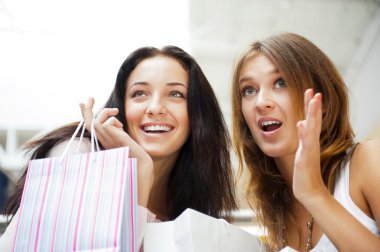 Two excited shopping woman together inside shopping mall. Horizo clipart