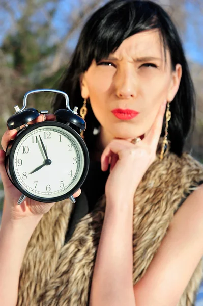 Surprised woman holding alarm clock outdoors — Stock Photo, Image